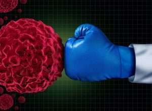 Cancer fight medical concept with an arm of a doctor wearing a blue boxing glove fighting a group of malignant human cells as a health care metaphor for researching a cure for dangerous tumors and therapy to remove illness.